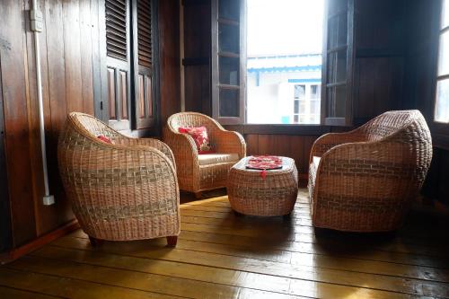 three wicker chairs and a table in a room at Rock and Wreck Dive Resort in Tanjungbinga