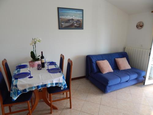 a dining room with a table and a blue couch at MARILENA in Fažana