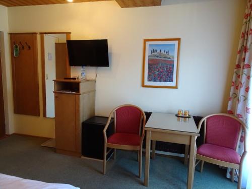a room with two chairs and a table and a tv at Pension Friedl in Innsbruck