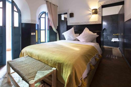 Un dormitorio con una cama grande y un banco en Riad Assala, en Marrakech