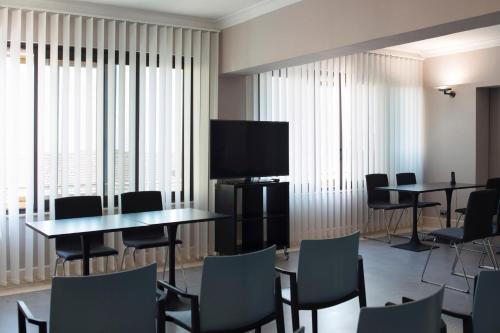 a room with tables and chairs and a flat screen tv at Principessa Mafalda in Messina