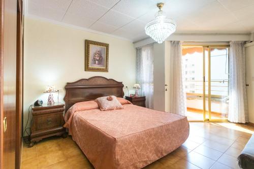 Un dormitorio con una cama grande y una lámpara de araña. en Playa 500m y Centro Pueblo 600m, Piscina, 4 Clim, 2 Parkings, en Santa Pola