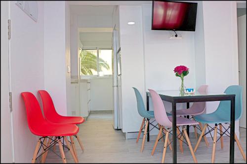a dining room with a table and colorful chairs at Apartamento Del Rio Playa in Cádiz