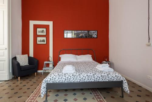 1 dormitorio rojo con 1 cama y 1 silla en Casette Umberto, en Catania