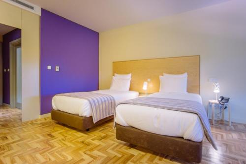 two beds in a room with purple walls and wooden floors at Hotel Rural Misarela in Geres