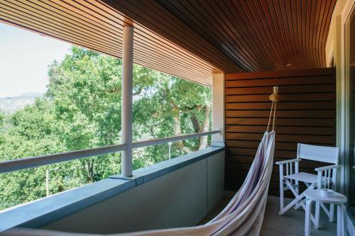 a hammock on the porch of a house with a large window at Hotel Rural Misarela in Geres