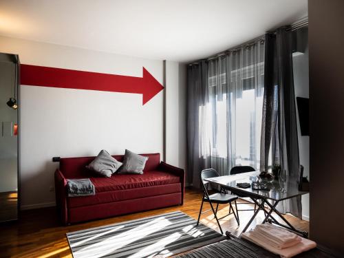 a living room with a red couch and an arrow on the wall at Carlotta Station Suite in Bologna