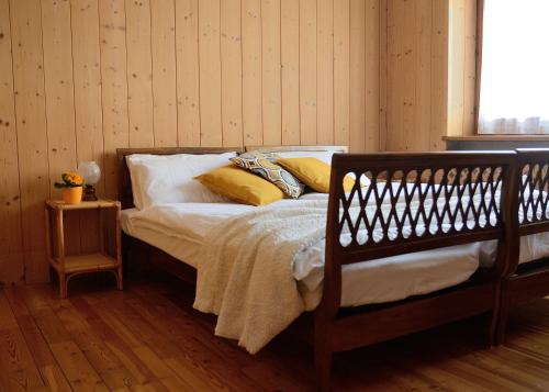 - une chambre avec un lit doté de draps blancs et d'oreillers jaunes dans l'établissement Casa vacanze Dos de Loré - Relax a due passi da Tovel, à Tuenno