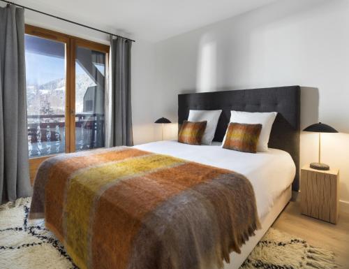 a bedroom with a large bed with a large window at La Résidence de L'Ours in Megève