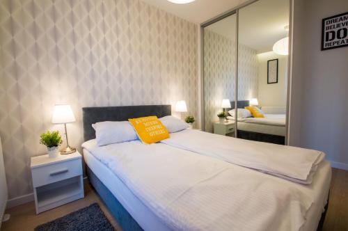 a bedroom with a large bed and a mirror at Fitness Apartment - Spa Sauna & Gym by Grand Apartments in Gdańsk