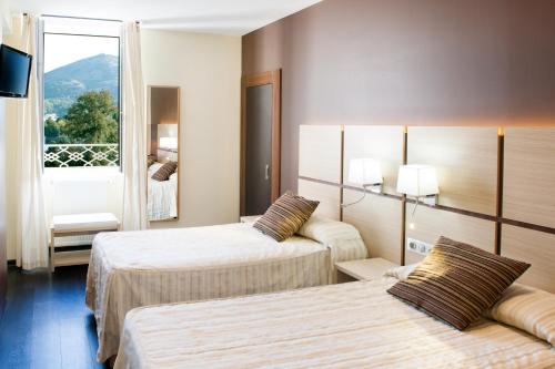 a hotel room with two beds and a window at Hôtel La Source in Lourdes