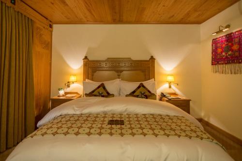 a bedroom with a large white bed with two lamps at Gilgit Serena Hotel in Gilgit