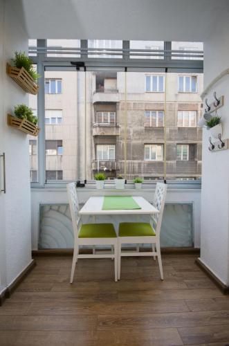 a table and chairs in a room with a large window at Belgrade CITY CENTER Apartments in Belgrade