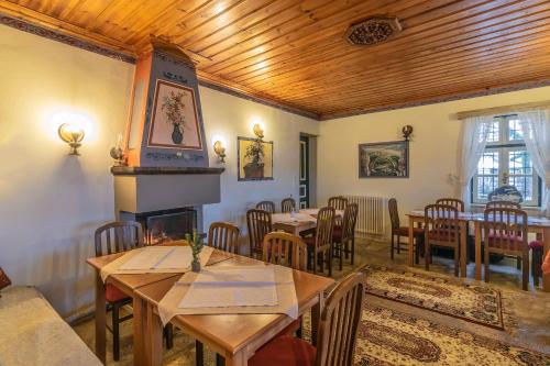 a dining room with tables and chairs and a fireplace at Guesthouse Selini in Vitsa
