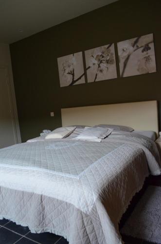 a bedroom with a white bed with pictures on the wall at B&B Hof Ter Haegen in Vollezele