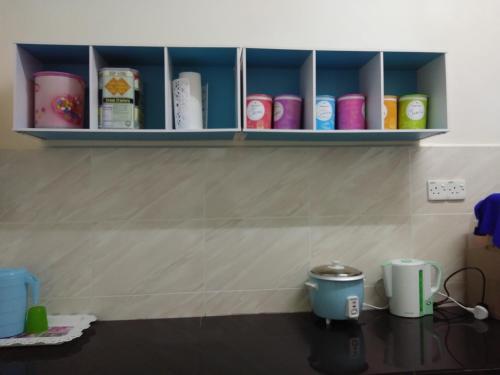 a kitchen counter with some cups on a shelf at Zah’ra Homestay in Kuala Lipis