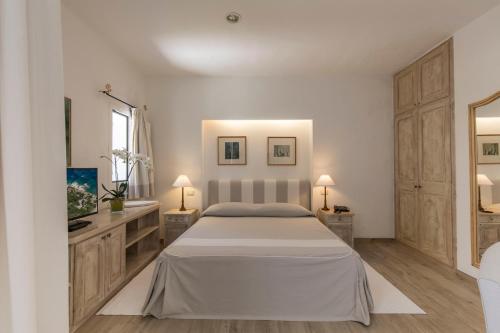 a white bedroom with a bed and two lamps at Hotel Grand Relais Dei Nuraghi in Baja Sardinia