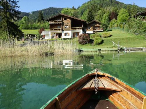 a boat in the water in front of a house at Chalets Zöhrer - Wohnen am Wasser in Weissensee