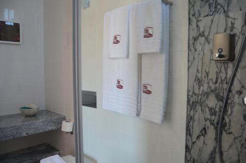 a bathroom with white towels and a shower at Entre Vinhas & Mar in Óbidos