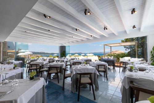 a restaurant with white tables and chairs with a view at Hotel Grand Relais Dei Nuraghi in Baja Sardinia