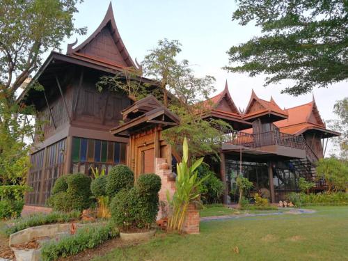 a large wooden house with a roof at Rueanrubkwan in Ang Thong