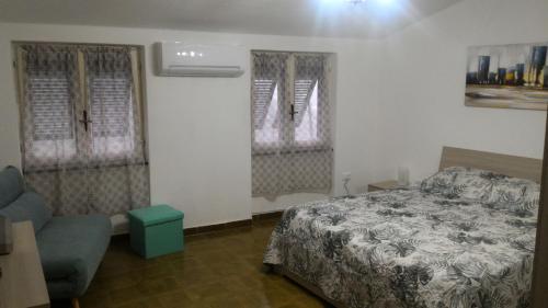 a bedroom with a bed and a chair and two windows at La casa di Andrea in Levanto