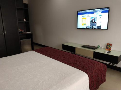 a bedroom with a bed and a tv on the wall at Hotel Merlott 70 in Medellín