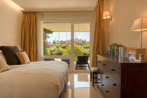een slaapkamer met een bed, een raam en een bureau bij Sotogrande Marina 2 Bedroom Luxury Ground Floor Apt in Torreguadiaro