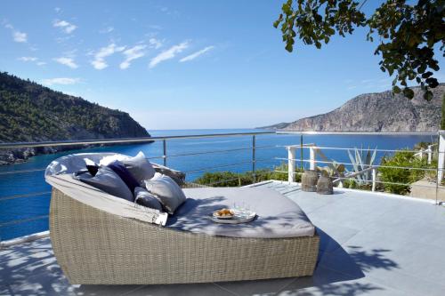 a wicker chair sitting on a balcony overlooking the water at Braunis Horio Villas in Asos