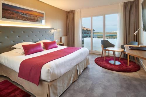 a hotel room with a large bed and a desk at Atlanthal in Anglet