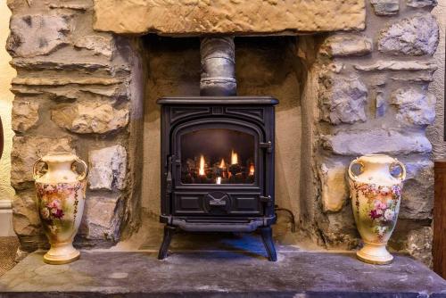 a fireplace with two vases in front of a stone wall at Labernum Cottage, Ingleton Village, Yorkshire Dales National Park, Famous Three Peaks, Near The Lake District, Pets Are Welcome, Direct Parking in front of the Cottage & Guest Parking in Ingleton