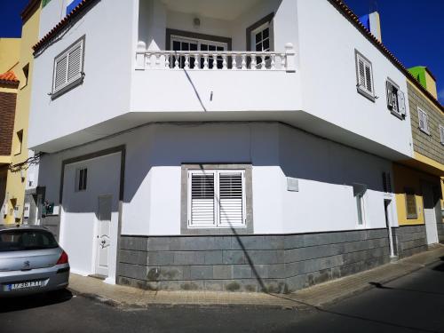 een wit huis met een auto ervoor geparkeerd bij Apartmento KA Sánchez in Vecindario