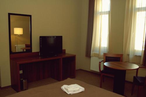 a hotel room with a tv and a table and a mirror at Fiáker Panzió in Zalaszentgrót