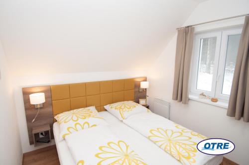 - une chambre avec un lit doté d'oreillers jaunes et blancs dans l'établissement Village Lipno Lakeside - Lipno 054, à Frymburk