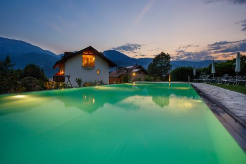 a swimming pool with a house in the background at Hotel Neuhausmühle in Vilpiano