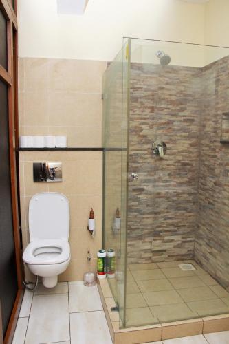 a bathroom with a toilet and a glass shower at Golden Beach Apartment A051 in Diani Beach