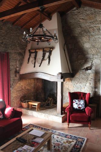 sala de estar con chimenea de piedra y silla roja en Retiro Da Avo Lídia - Turismo Rural, en Mendiga