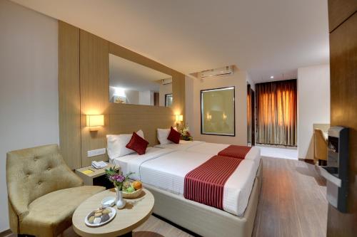 a hotel room with a bed and a chair at La Sara Pride in Bangalore