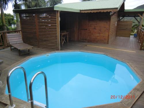 a large blue swimming pool on a deck with a hut at villa marguerita in Deshaies