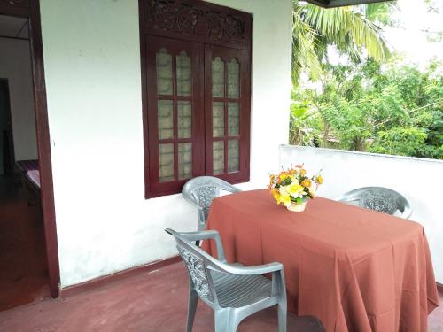 a red table with chairs and a vase of flowers on it at Southern Beach Surf Lodge in Ahangama