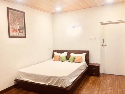 1 dormitorio con 1 cama con sábanas y almohadas blancas en West Valley Farm Villa, en Lavasa