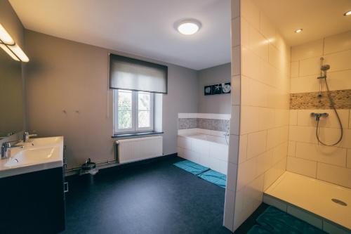 a bathroom with a tub and a sink and a shower at Chez Marraine in Nassogne