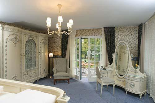 a room with a mirror and a bed and a chair at Hotel Buchenhof in Worpswede