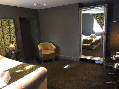 a bedroom with a mirror and a chair and a bed at The Peacock in Bakewell