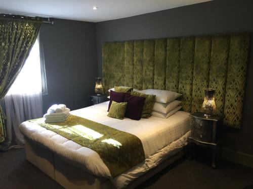 a bedroom with a large bed with a green headboard at The Peacock in Bakewell