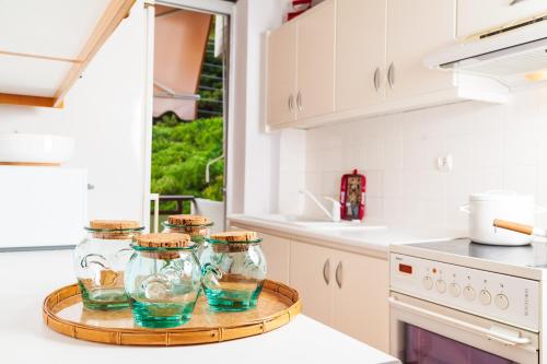 a white kitchen with four glass jars on a tray at F & B Summer Collection - Kassandra - Mola Kaliva in Mola Kalyva