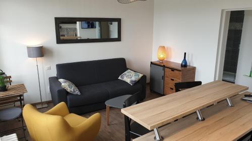 a living room with a couch and a table at Le Charmant Studio Maupassant in Fécamp