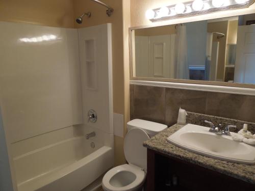a bathroom with a sink and a toilet and a mirror at Sifting Sands Motel in Ocean City