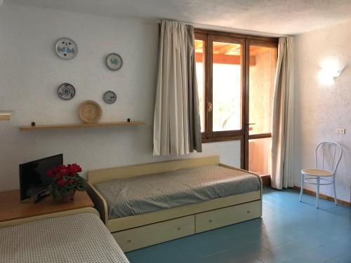 a bedroom with a bed and a tv and a window at Centro Vacanze Cugnana Verde in Marina di Portisco