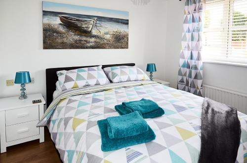 sypialnia z łóżkiem z niebieskimi ręcznikami w obiekcie Sunshine Corner w mieście West Mersea